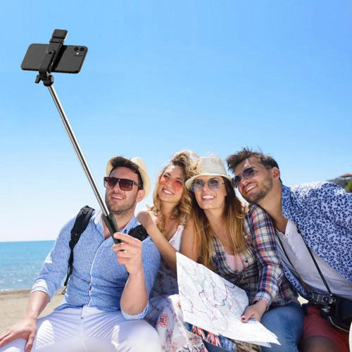 Group taking beach selfie with smartphone selfie stick, travel gear for vacation photos