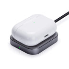 White wireless earbuds case charging on black Qi pad with green LED indicator
